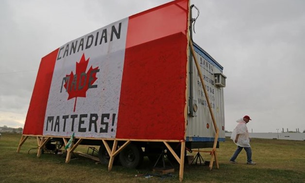 A striking member of the auto workers union Unifor walks to a picket line past a trailer covered by with a Canadian flag reading "Canadian Made Matters!", outside the General Motors Company (GM) CAMI assembly plant in Ingersoll, Ontario, Canada October 13