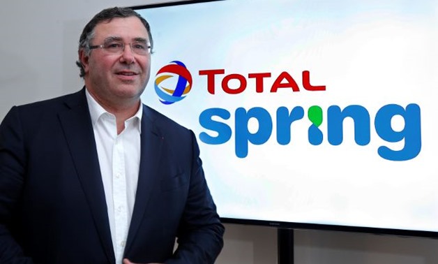 Total CEO Patrick Pouyanne poses next to the logo of Total Spring during a news conference in Paris - REUTERS