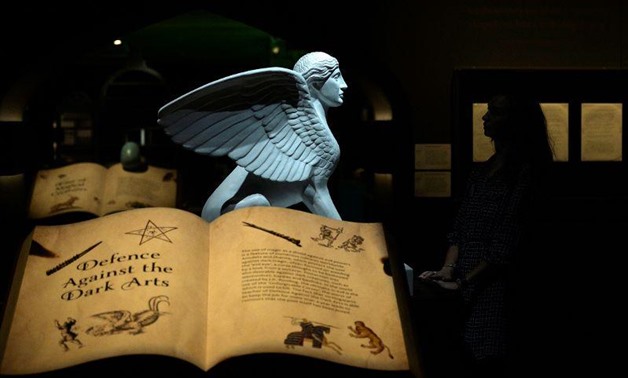 A gallery assistant poses for photographs during the press preview of the exhibition "Harry Potter: A History of Magic" at the British Library in London, Britain, October 18, 2017. REUTERS/Mary Turner