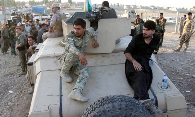 Kurdish Peshmerga fighters sit on a military vehicle north of Kirkuk -- REUTERS