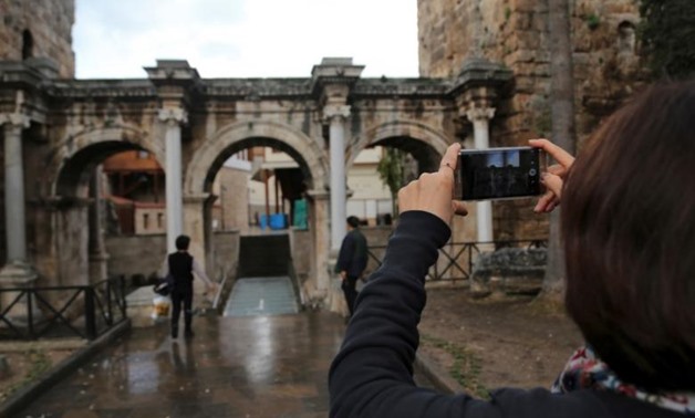 A tourist takes a picture of the Hadrian's Gate, a triumphal arch in the Mediterranean - Reuters
