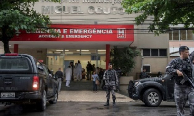 © AFP | Policemen stand guard at the entrance of Miguel Couto Hospital, where a Spanish tourist was taken after being shot by a police
