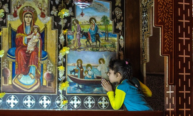 A girl kisses an iconostasis in Muharraq Monastery in Asyut - Maher Eskandar