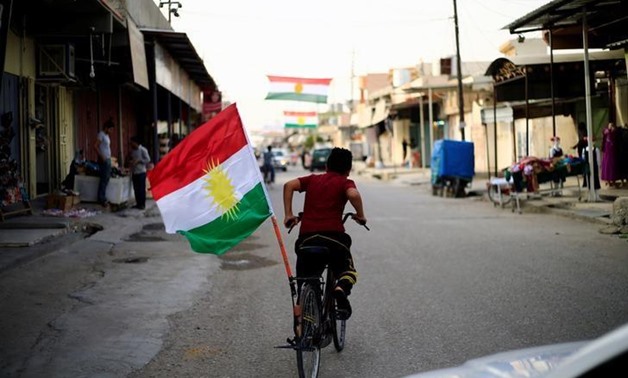 A boy rides a bicycle with the flag of Kurdistan in Tuz Khurmato, Iraq September 24, 2017. REUTERS/Thaier Al-Sudani