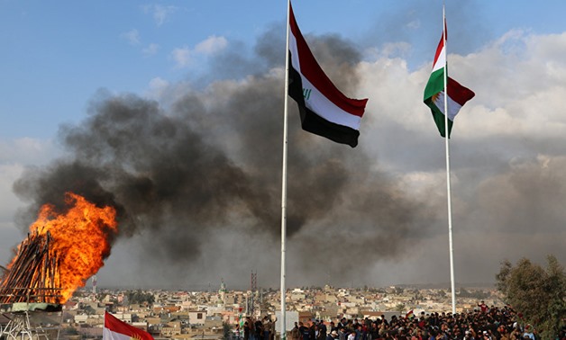 Kurdish and Iraqi flags sway in the wind as a bonfire burns during the Nowruz spring festival celebrations in Kirkuk, north of Baghdad. AFP/Marwan Ibrahim 