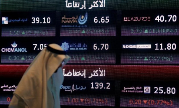 An investor walks past a screen displaying stock information at the Saudi Stock Exchange (Tadawul) in Riyadh, Saudi Arabia June 29, 2016.