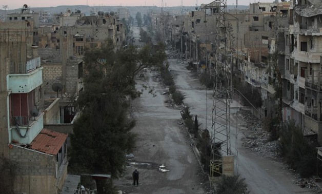A man walks along a deserted street filled with debris in Deir al-Zor, eastern Syria  - REUTERS