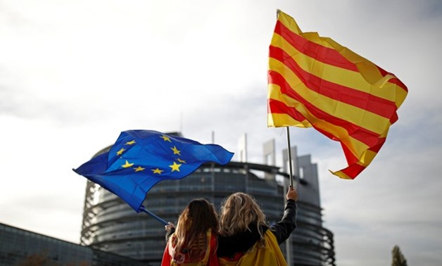 Women hold Spanish and Catalan flags during a gathering against Catalonia independence in front of the European Parliament in Strasbourg - REUTERS
