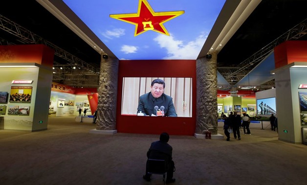 A visitor watches a video showing Chinese President Xi Jinping at a military meeting during an exhibition displaying China's achievements for the past five years. Reuters