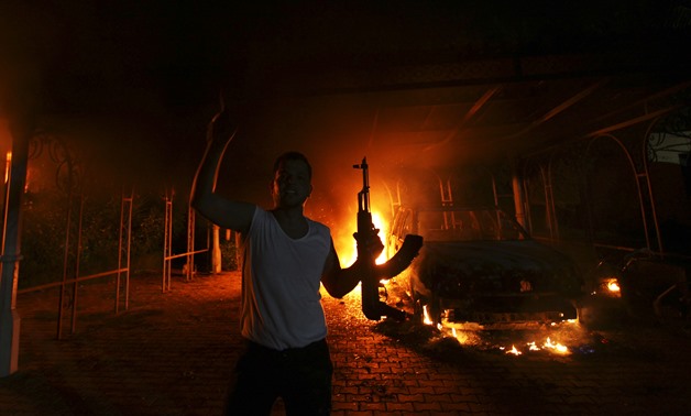 A protester reacts as the U.S. Consulate in Benghazi is seen in flames - REUTERS