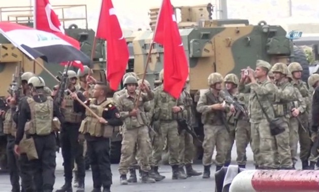 Iraqi and Turkish soldiers wave flags at the Habur Border Gate between Turkey and Iraq in this still image taken from video - REUTERS