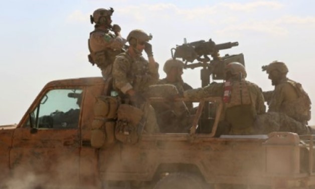 © AFP | Men identified by Syrian Democratic forces as US special operations forces ride in the back of a pickup truck in the village of Fatisah in the northern Syrian province last year

