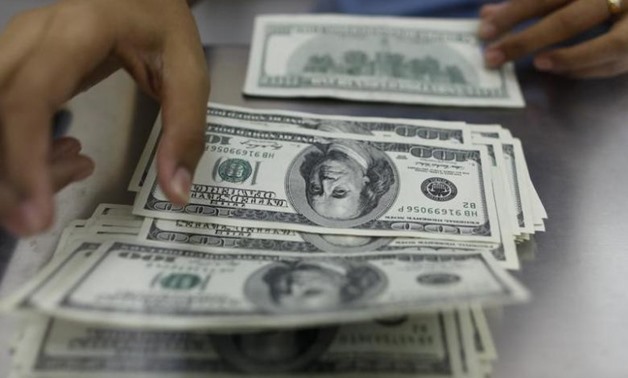A woman counts U.S. dollars at a money changer in Yangon May 23, 2013 - REUTERS