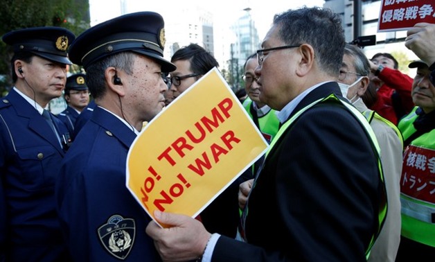 Police officers stand guard in front of protesters during a rally against U.S. President Donald Trump's visit to Japan, near the U.S. Embassy in Tokyo - REUTERS