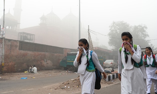 Indian schoolchildren cover their faces as they walk to school amid heavy smog in New Delhi on November 8, 2017 - AFP