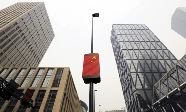 A Chinese national flag is seen among buildings at the Yujiapu financial centre, in Tianjin, China February 22, 2016. REUTERS/Jason Lee
