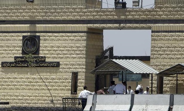 Policemen and people walk in front of the main gate of Tora prison in Cairo. PHOTO: Reuters 