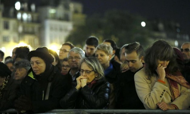 People gather outside Notre Dame Cathedral where a mass is held following a series of deadly attacks in Paris, November 15, 2015. REUTERS/Gonzalo Fuentes