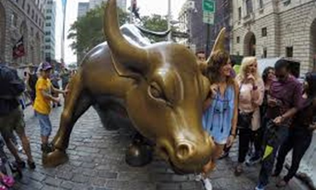 People pose next to the Wall Street Bull in the financial district in New York, U.S., August 10, 2017. REUTERS/Eduardo Munoz - RC1AD75585E0
