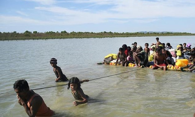 Rohingya Muslim refugees seen using a makeshift raft to cross from Myanmar into Bangladesh, where -AFP