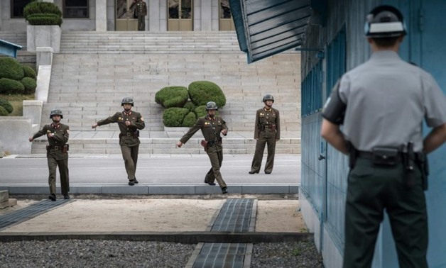 A South Korean soldier (R) watches North Korean soldiers walking towards the military demarcation line separating North and South Korea at the truce village of Panmunjom