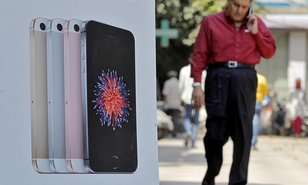 A man speaks on his mobile phone as he walks past an Apple iPhone advertisement billboard on a street in New Delhi, India, April 25, 2016. REUTERS/Anindito Mukherjee/File Photo