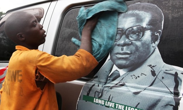 Youth washes a minibus adorned with picture of President Robert Mugabe at a bus terminus in Harare, Zimbabwe, November 15, 2017. REUTERS/Philimon Bulawayo 
