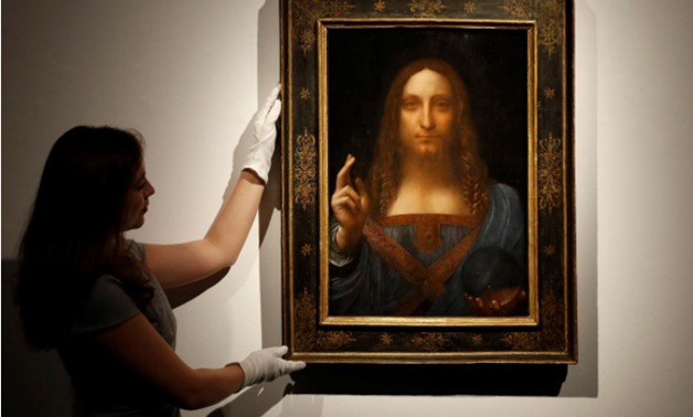 Members of Christie's staff pose for pictures next to Leonardo da Vinci's "Salvator Mundi" painting which will be auctioned by Christie's in New York in November, in London, Britain October 24, 2017 - REUTERS/Peter Nicholls