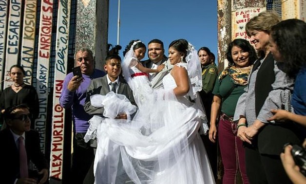 Bride Evelia Reyes and groom Brian Houston pose for pictures after marrying at an open gate on the US-Mexico border at Playas de Tijuana, Mexico - AFP