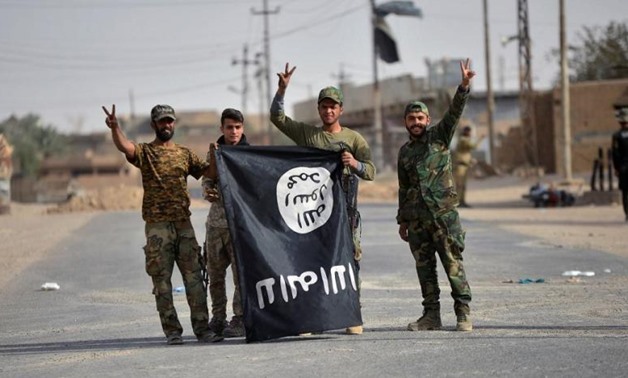Popular Mobilization Forces fighters carry an ISIS flag downward after liberating the city of al-Qaim, Iraq November 3, 2017. REUTERS