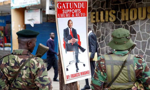 Policemen stand near a poster depicting Kenya's President Uhuru Kenyatta in Nairobi, Kenya November 20, 2017. REUTERS/Baz Ratner