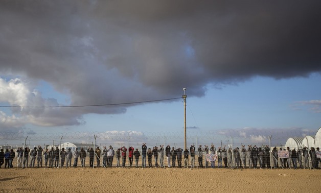 African asylum seekers, who entered Israel illegally via Egypt, lean at the fence of the Holot detention center in Israel's southern Negev Desert, on Feb. 17, 2014 as they join other migrants who came to protest outside the detention facility - AFP
