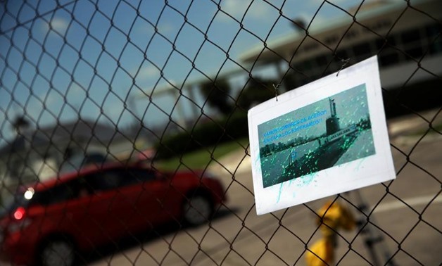 A car enters the Argentine Naval Base where the missing at sea ARA San Juan submarine sailed from as a picture of it hangs on a fence in Mar del Plata, Argentina November 19, 2017. REUTERS/Marcos Brindicci
