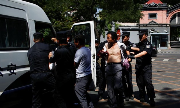 Police detain a man as people protest against a local authoritiy's decision to reassign their children to an undesired school in Beijing, China June 14, 2017. REUTERS/Thomas Peter
