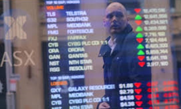 An investor is reflected in a window displaying a board showing stock prices at the Australian Securities Exchange (ASX) in Sydney, Australia, July 17, 2017. REUTERS/Steven Saphore