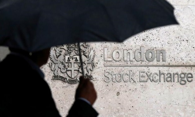 FILE PHOTO: A man shelters under an umbrella as he walks past the London Stock Exchange in London, Britain August 24, 2015. REUTERS/Suzanne Plunkett/File Photo

