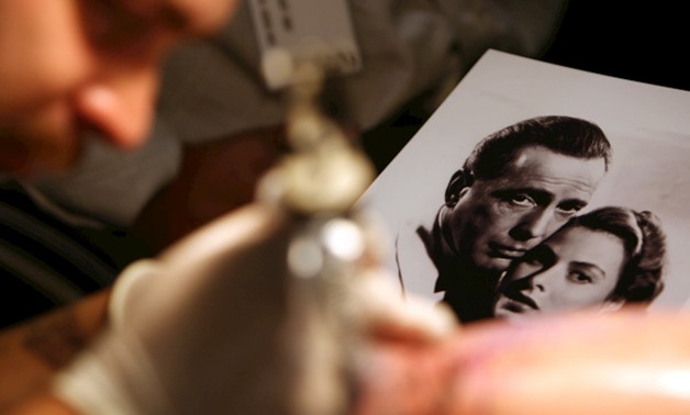 This file photo taken on September 15, 2006 shows a tatoo artist working from a portrait of Hollywood legends Humphrey Bogart and Ingrid Bergman in Los Angeles. This weekend marks the 75th anniversary of the premiere of "Casablanca," a timeless story of l