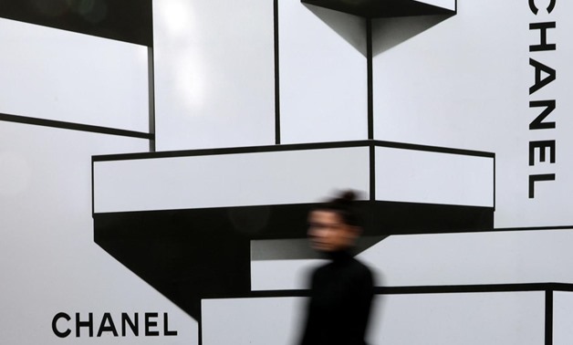 A woman walks past a wall with logos of French luxury goods maker Chanel in Nice, France, February 22, 2017. REUTERS/Eric Gaillard/File Photo