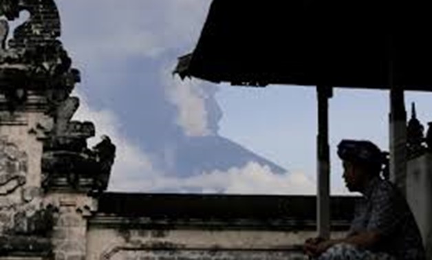 A Balinese man sits as Mount Agung volcano erupts at Lempuyang Temple in Karangasem, Bali, Indonesia November 27, 2017. REUTERS/Johannes P. Christo
