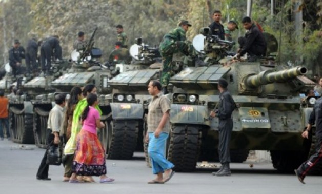 © AFP/File | Bangladeshis gather beside tanks manned by army soldiers near the Bangladesh Rifles headquarters in Dhaka on February 26, 2009
