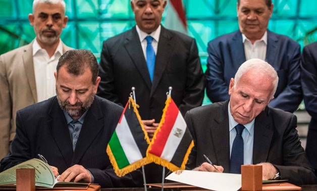 Fatah's Azam al-Ahmad (R)and Saleh al-Arouri of Hamas (L) sign a reconciliation deal at the Egyptian intelligence services headquarters in Cairo on October 12, 2017 – AFP 