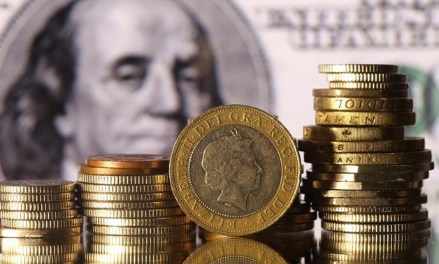 Pound coins are seen in front of a displayed U.S. 100 dollar banknote in this picture illustration taken January 18, 2017. REUTERS/Dado Ruvic/Illustration
