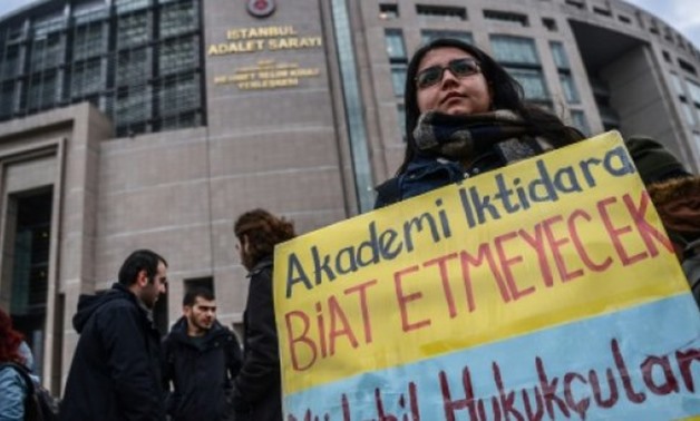  "Academia will not bow to the government," reads a placard held by a protester - AFP
