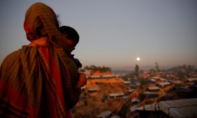 A Rohingya refugee looks at the full moon with a child in tow at Balukhali refugee camp near Cox's Bazar, Bangladesh - REUTERS/Susana Vera