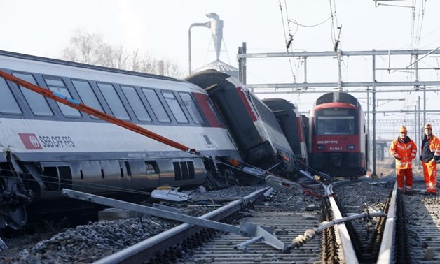 Rescue workers stand next to a derailed train after two trains collided near Rafz around 30 km (18 miles) from Zurich February 20, 2015. REUTERS/Arnd Wiegmann
