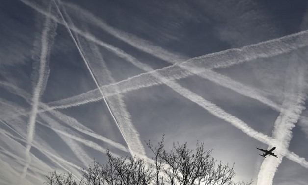 A passenger plane flies through aircraft contrails in the skies near Heathrow Airport in west London, April 12, 2015. REUTERS/Toby Melville
