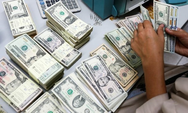 REUTERS- A bank employee counts U.S. dollar notes