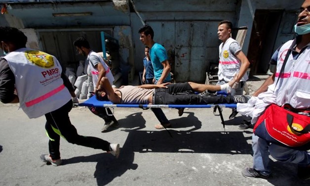 Medics carry an injured Palestinian during clashes with Israeli troops in the West Bank Al-Fawwar refugee camp, south of Hebron August 16, 2016. REUTERS/Mussa Qawasma
