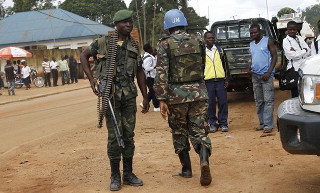A peacekeeper serving in the United Nations Organization Stabilization Mission in the Democratic Republic of the Congo (MONUSCO) and a Congolese soldier stand guard as residents gather following recent demonstrations in Beni in North Kivu province, Octobe