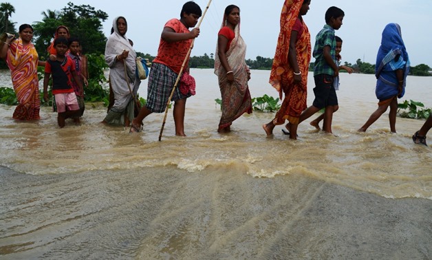 Indian flood victims wade through flood waters to collect relief materials in Chitnan village, around 60 km West of Kolkata, on July 28, 2017. (AFP/Dibyangshu Sarkar)

